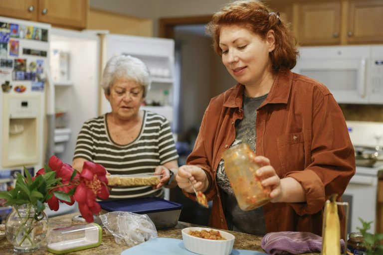 Two women preparing food together in a shared kitchen