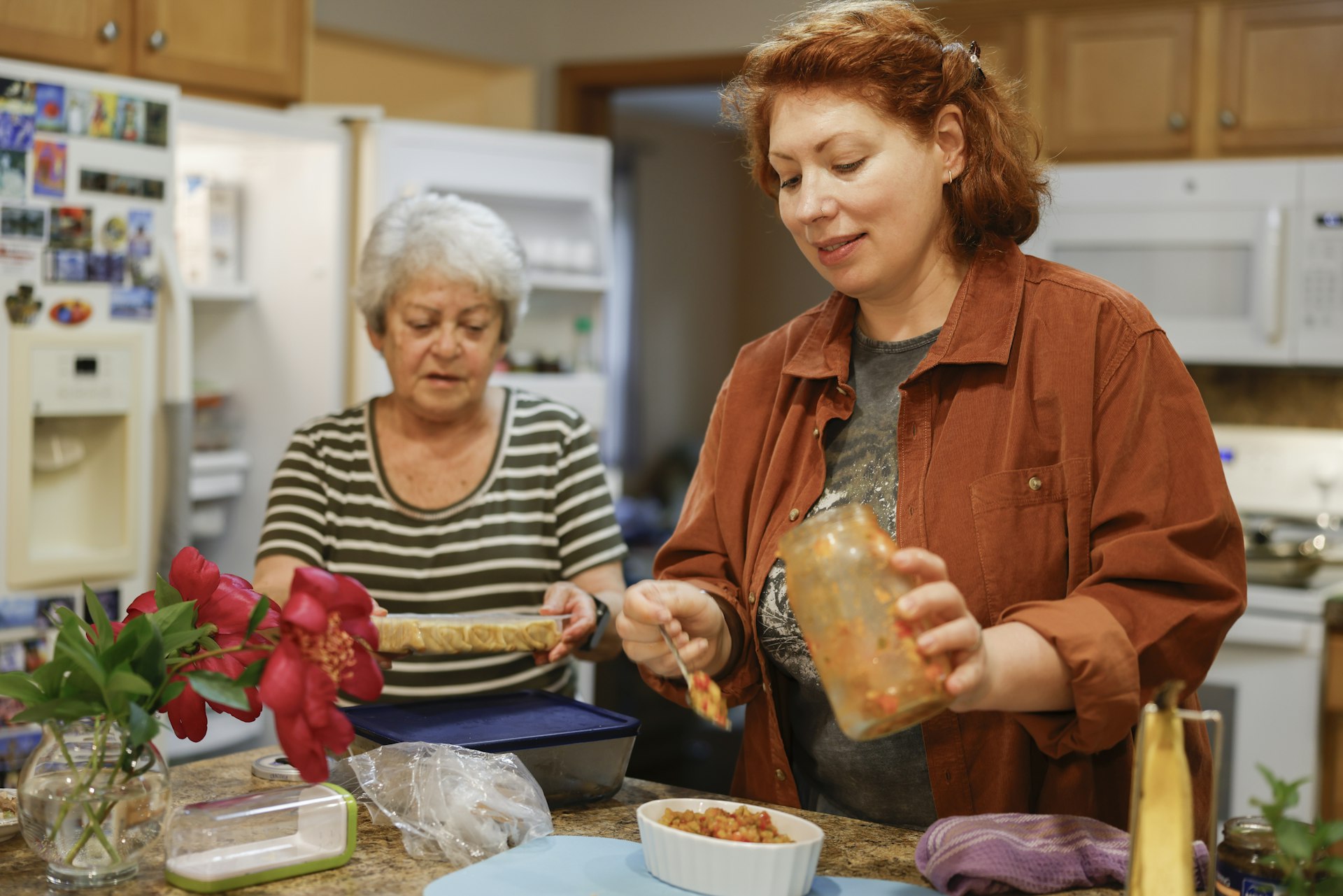 Two women preparing food together in a shared kitchen