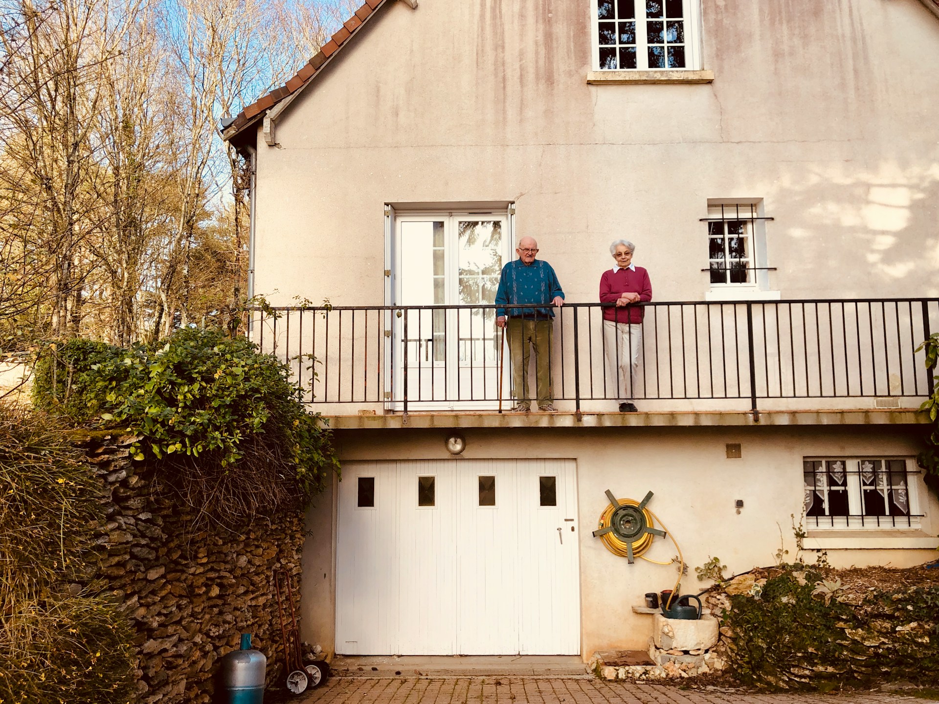 Older couple standing outside their home
