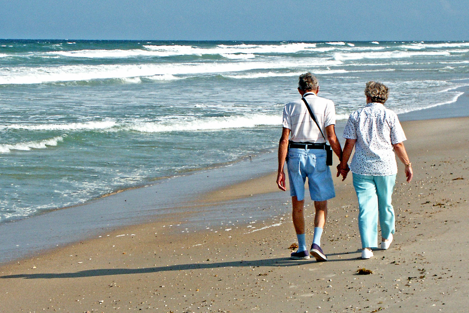 Older couple walking hand in hand on the beach